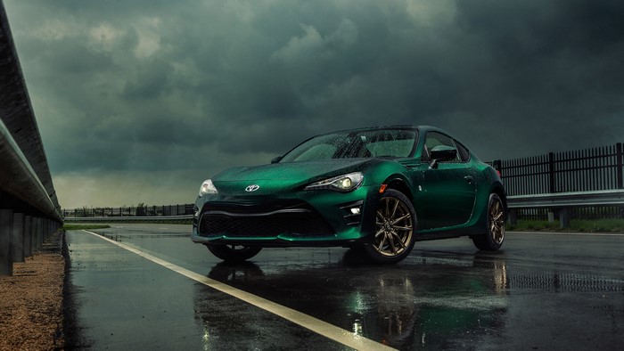 Green Toyota GT86 with colored wheels on a wet road