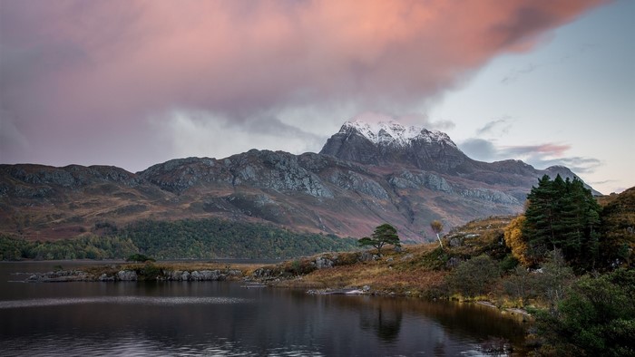 Snow-capped mountain range over a lake at sunset