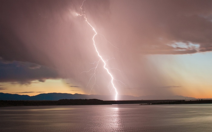 Lightning strike over a lake at sunset