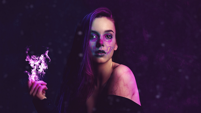 Woman with skull face paint and purple fire