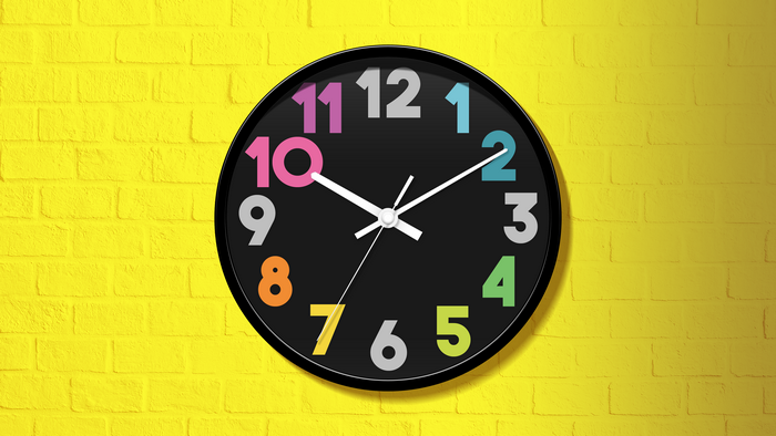 Colorful numbers clock on yellow brick wall