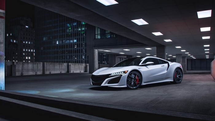 White Acura NSX sports car parked in a parking garage at night