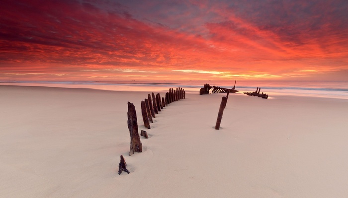 Shipwreck remains on a beach at sunset