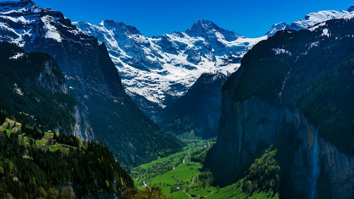 Valley with snow-capped mountains and a village in Switzerland