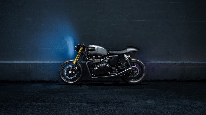Triumph motorcycle parked against a dark wall