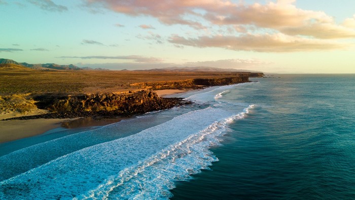 Aerial view of Fuerteventura coastline with waves and mountains