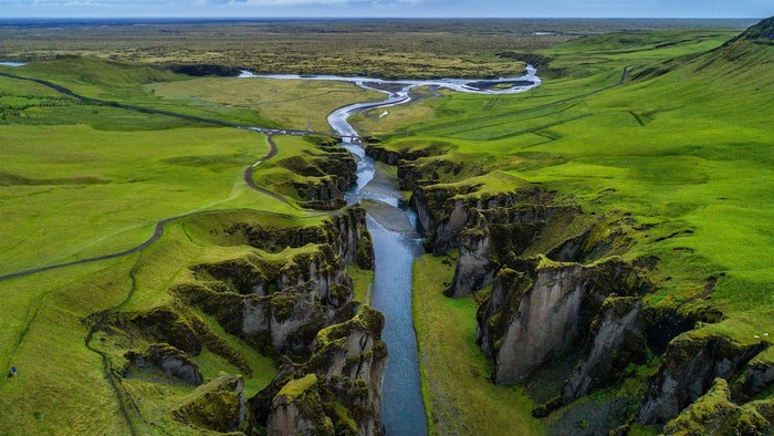 Aerial view of a river flowing through a green canyon in Iceland