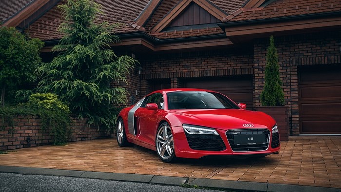Red Audi R8 parked in front of a brick house