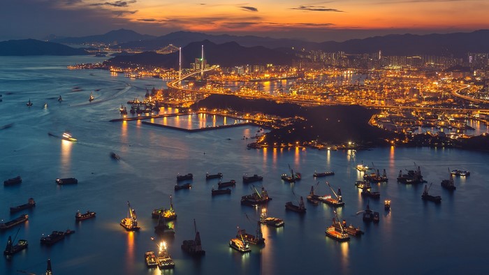 Hong Kong harbor at sunset with many ships and city lights