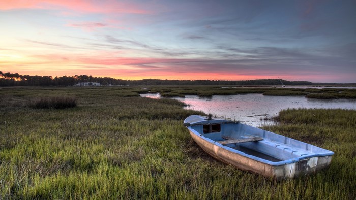 Boat on a grassy marsh at sunset