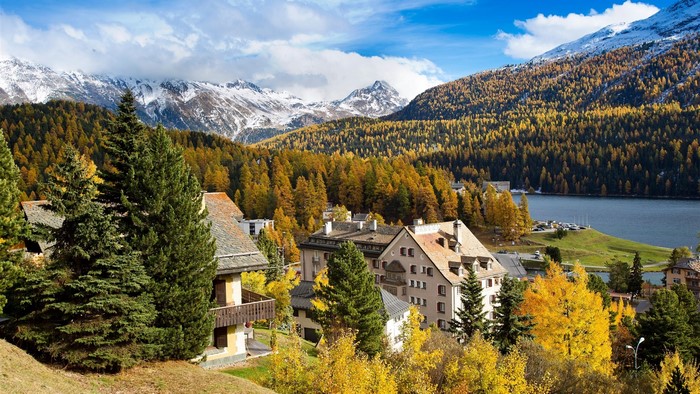 Autumn mountain village with lake and snow-capped peaks