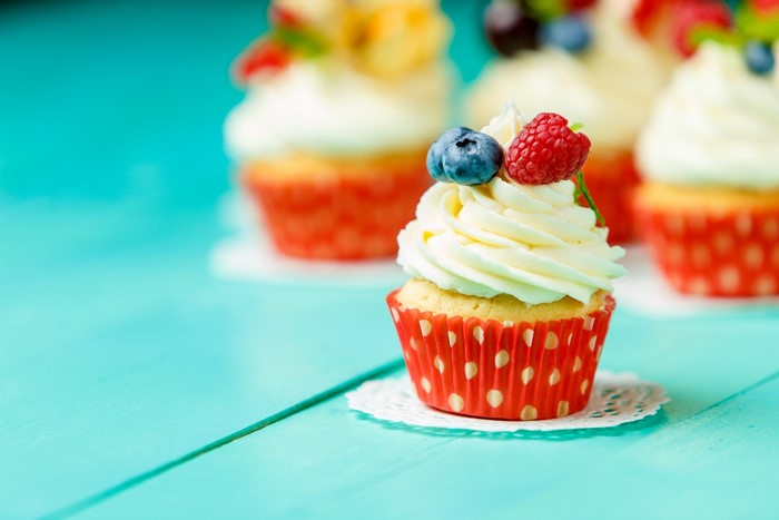 Cupcakes with berries on a cyan table