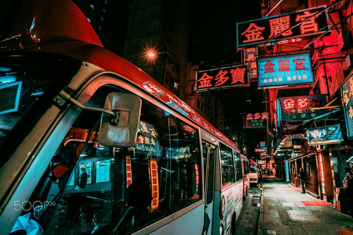 Hong Kong street at night with neon signs and buses