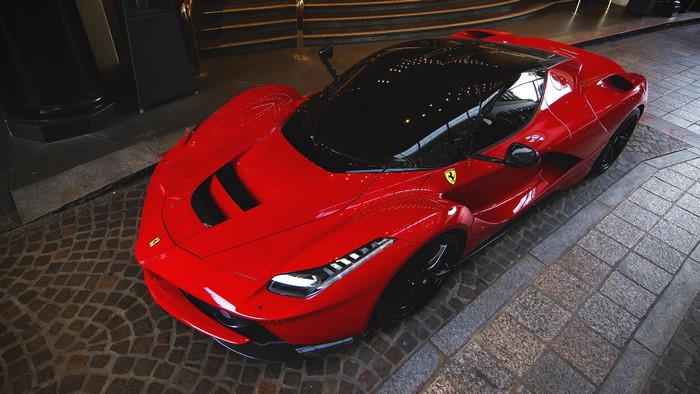Red Ferrari LaFerrari parked on cobblestone street