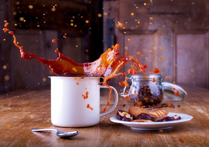 Coffee splash in a mug with cookies and coffee beans