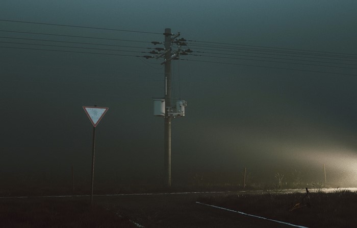 Road sign and power pole in mist with car headlights