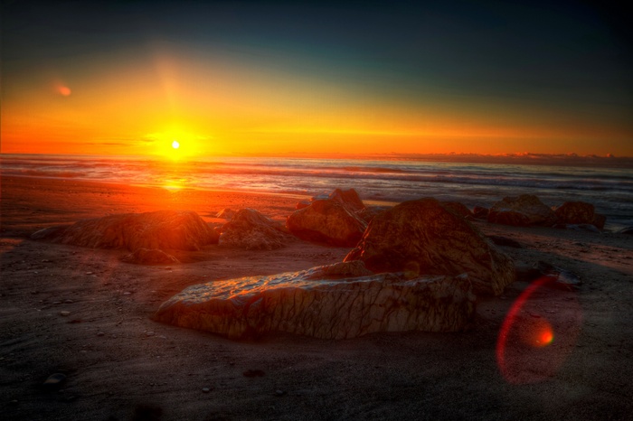 Sunset over a rocky beach with ocean waves