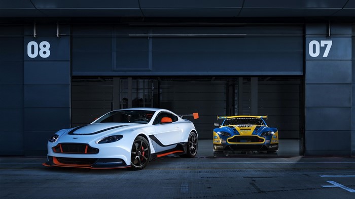 Two Aston Martin Vantage race cars in garages