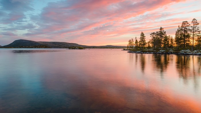Sunset over a lake with trees and mountains in Sweden