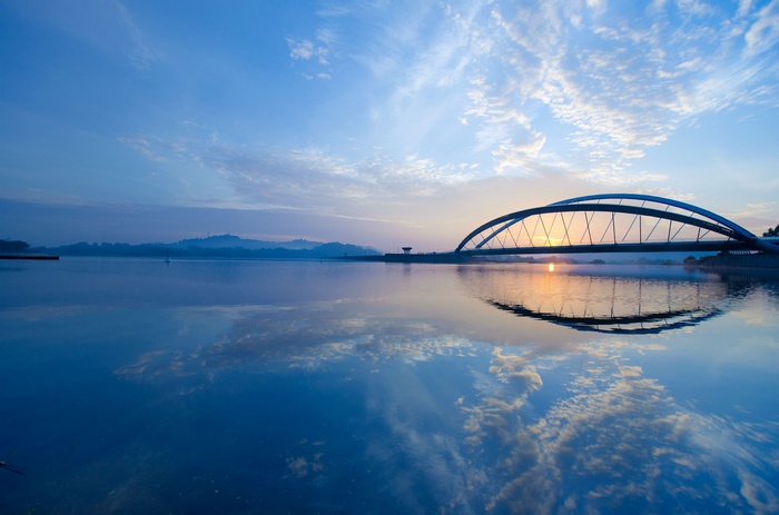 Bridge over a calm lake at sunrise with reflections