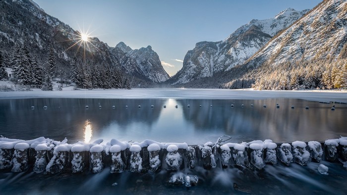 Winter sunrise over a frozen lake and snow-covered mountains