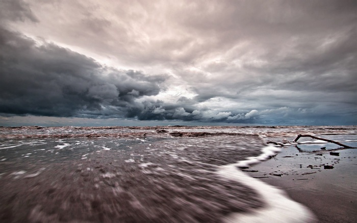 Stormy clouds over a dark, choppy sea and beach