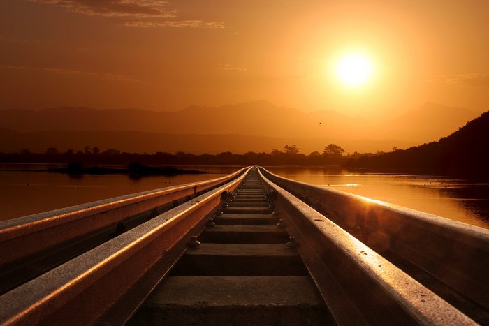 Railway tracks at sunset over water