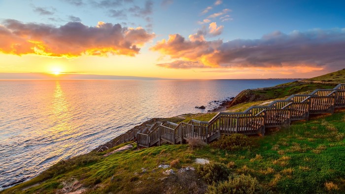 Wooden stairs leading down to the ocean at sunset