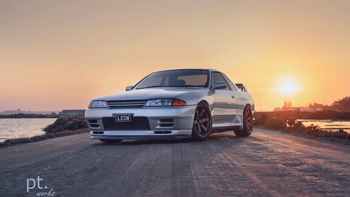 Silver Nissan Skyline GT-R R32 on dirt road at sunset