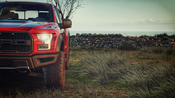 Red Ford F-150 Raptor by a stone wall and the sea