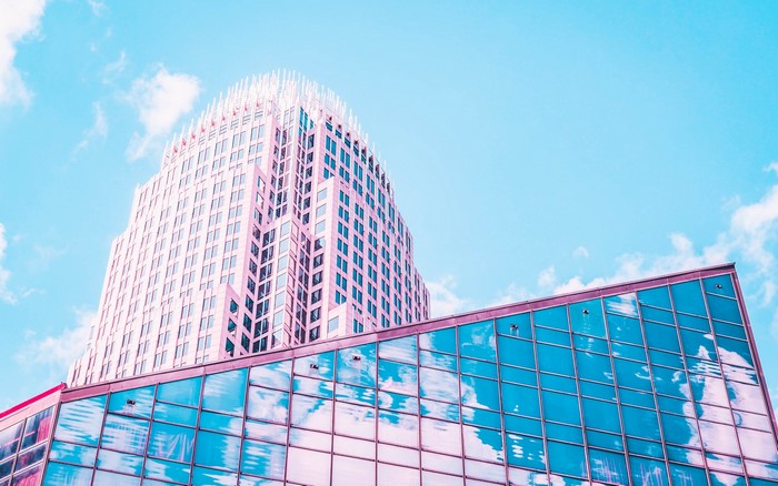 Pink skyscraper and glass building against blue sky