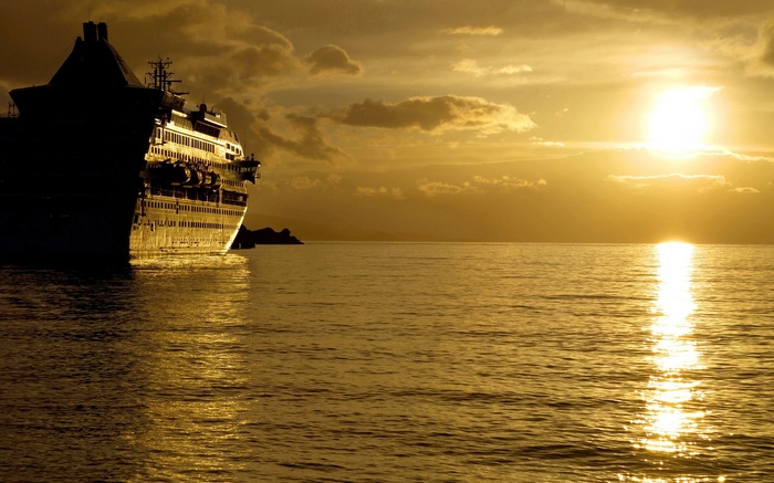 Cruise ship sailing on the ocean at sunset