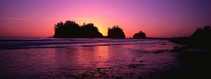 Sunset over a rocky coastline with islands