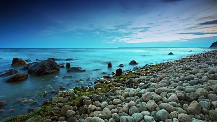 Long exposure of Baltic Sea coast in Germany with rocks and clouds