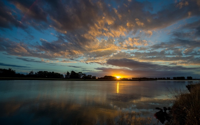 Sunset over a calm river with colorful clouds