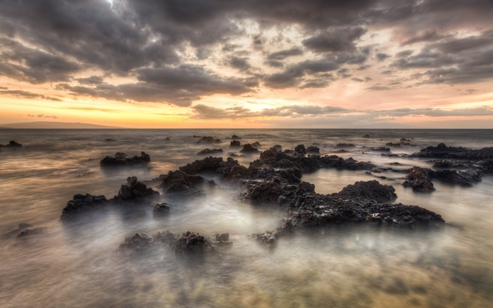Rocky coastline at sunset with dramatic clouds
