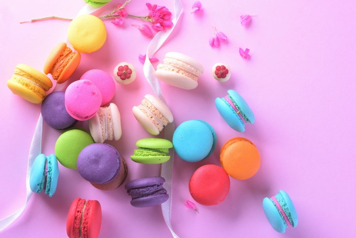 Colorful macarons and flowers on a pink background