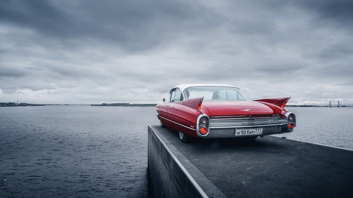 Red Cadillac de Ville parked by the water