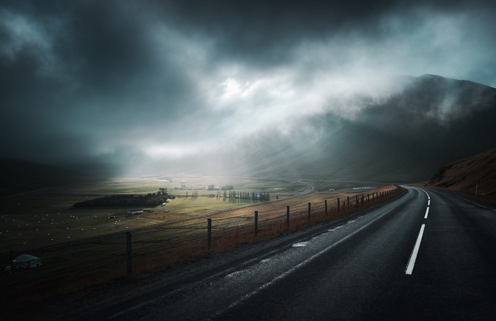 Dark landscape with a road and stormy sky