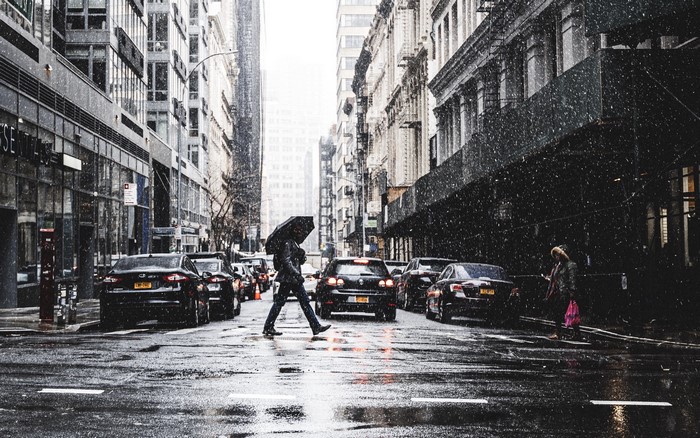 Person with umbrella crossing street in rainy New York City
