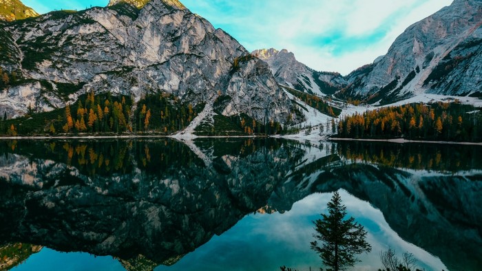 Lake reflecting mountains and autumn trees under a blue sky