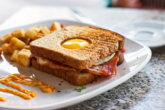 Sandwich with egg, bacon, and potatoes on a plate