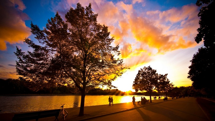 Sunset over a park with a lake and people