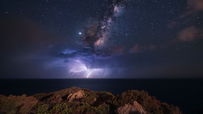 Milky Way and lightning over the ocean