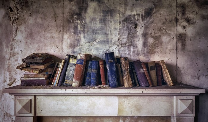 Old books on a dusty shelf in an abandoned room