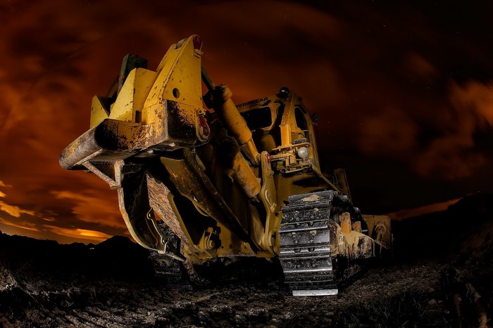 Yellow bulldozer at night with orange sky