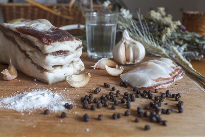 Salo, garlic, peppercorns, salt, and vodka on a wooden board