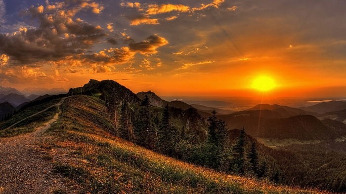 Sunset over a mountain range with a path