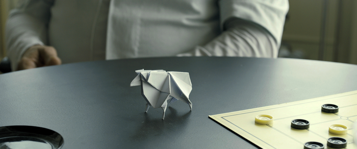 Origami sheep on a table with a board game