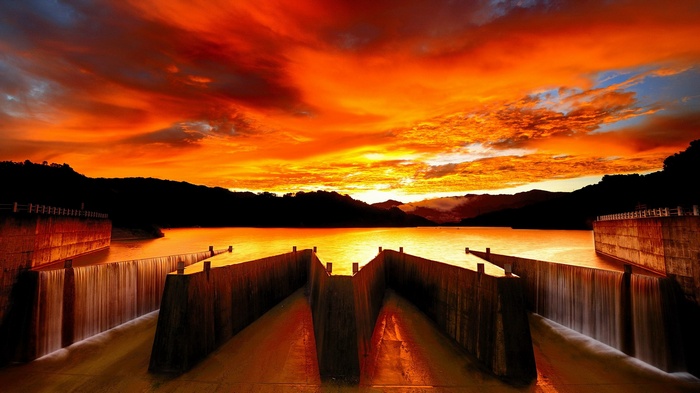 Dam with water flowing at sunset
